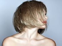 portrait of a beautiful woman in short blond bob with messy wet hair on studio background
